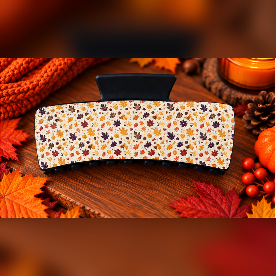 Autumn Leaves claw clip with scattered maple leaves and acorns on cream, on a wooden surface with fall foliage