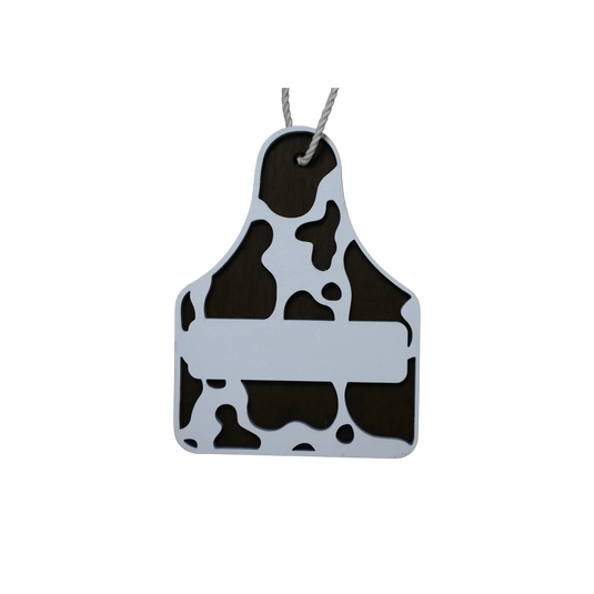 Trail and Timber Co cow tag ornament featuring a brown and white cow print design with a blank space for personalization
