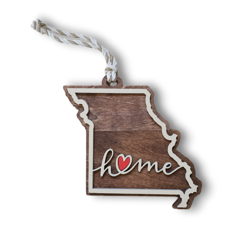 Load image into Gallery viewer, Trail and Timber Co. laser-cut wooden Missouri state ornament with Home inscription and a small red heart detail.
